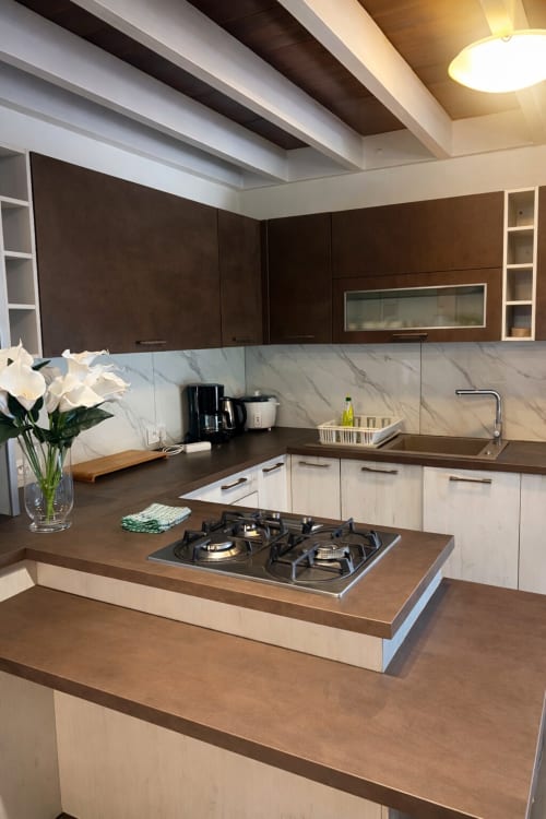 Cuisine moderne de la Villa Vaipipiha à Aimehome, Paopao, avec cuisinière au gaz, dosseret en marbre et mobilier en bois foncé
