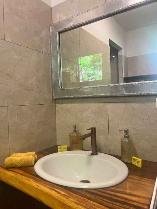 Salle de bains élégante avec vasque ronde blanche, robinet noir et miroir décoratif à la Villa Vaipipiha, Aimehome, Paopao