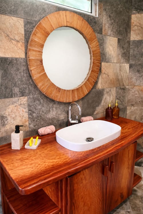 Vasque en bois élégante et miroir rond dans la salle de bain moderne de la Villa Vaipipiha à Paopao