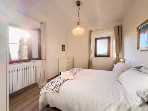 Bright bedroom at Tuscan Sun Stays with white bedding, pendant light, radiator, and views in Volterra