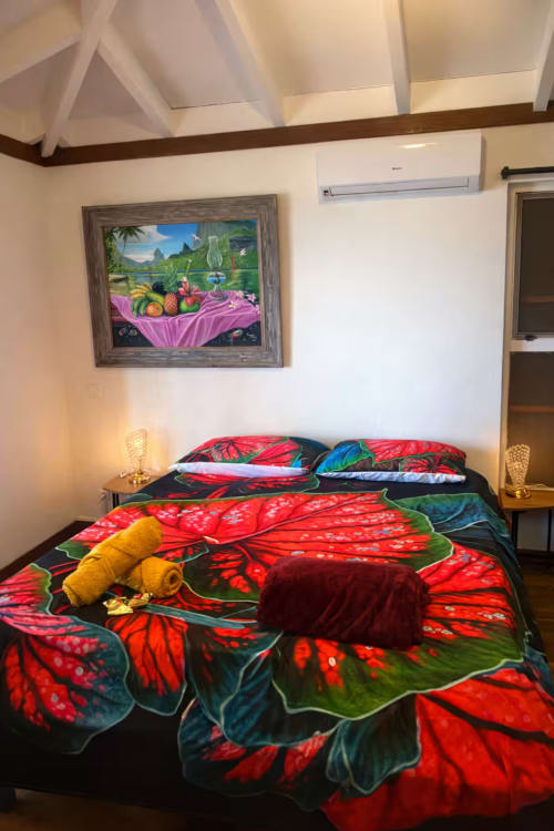 Chambre tropicale colorée à la Villa Vaipipiha à Paopao avec literie aux fleurs rouges et tableau vue sur l'océan