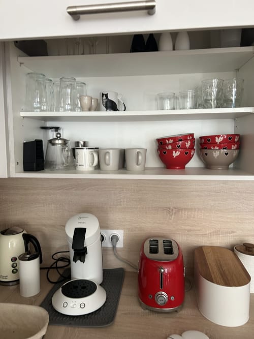 Dream Properties kitchenette in La Plagne Tarentaise with appliances, glassware, and red accents on wooden countertop