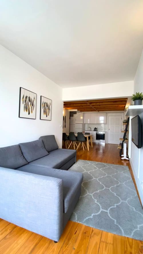 Moderno estúdio no Bom Porto Apartments com sofá cinzento, piso em madeira, sala de jantar, cozinha e arte emoldurada na parede