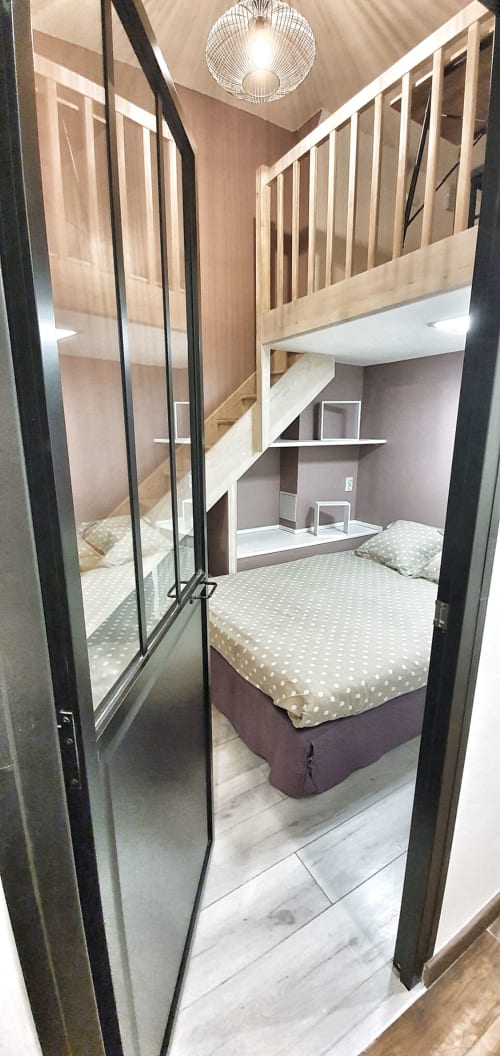 Chambre loft contemporaine à Paris 16 avec mezzanine, portes vitrées, literie à pois et équipements modernes