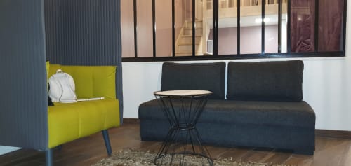 Salon d'appartement parisien moderne avec fauteuil jaune, canapé anthracite et table d'appoint au design contemporain
