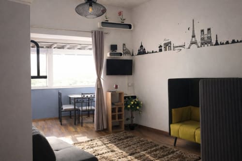 Appartement parisien moderne avec fresque murale de la skyline, salon meublé aux accents jaunes, salle à manger et vue sur la ville