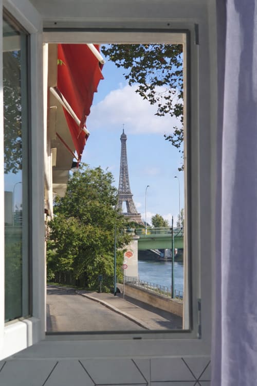Vue de la Tour Eiffel depuis le porche d'un appartement à Paris 16e, avec auvent rouge et Seine visible