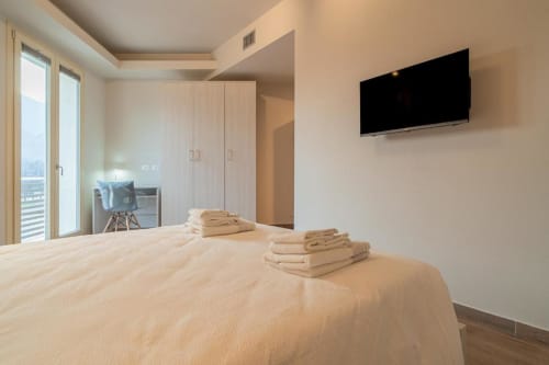Camera moderna a Le Alpi con vista montagna, TV schermo piatto, balcone e asciugamani ordinatamente piegati sul letto