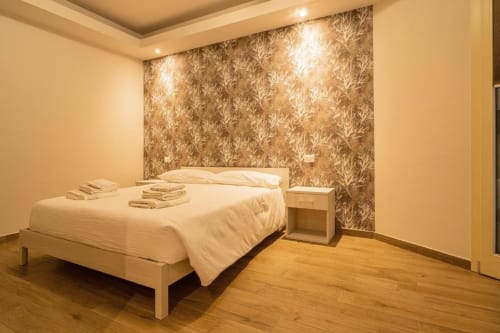 Camera Tonale presso Le Alpi bed & living a Cividale Camuno con letto matrimoniale, biancheria bianca e parete con motivi decorativi