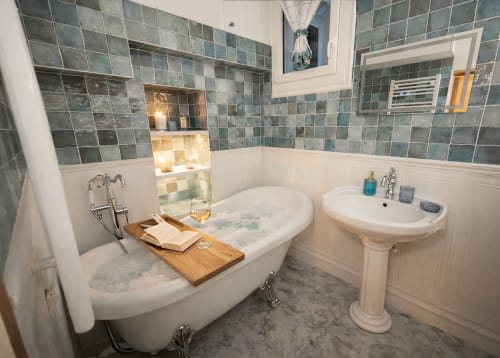 Salle de bains luxueuse dans un appartement parisien avec baignoire îlot, lavabo sur piédestal, murs carrelés et vue sur la ville