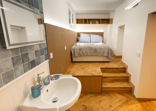 Appartement parisien moderne avec lavabo, escalier en bois, lit aux oreillers blancs et literie rayée