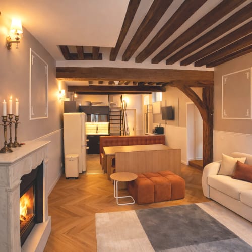 Élégant appartement parisien avec poutres apparentes, cheminée, parquets et mobilier contemporain fusionnant charme historique et