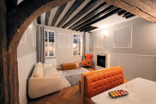 Appartement parisien moderne avec poutres apparentes, sièges orangés, cheminée et vue sur la ville à l'hôtel ATHEA