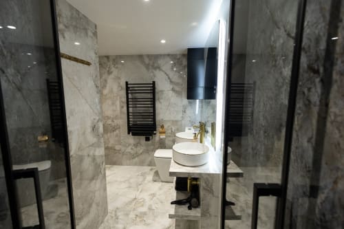Salle de bain moderne en marbre dans un appartement parisien avec double vasque, robinetterie noire et douche à effet pluie à ATHEA BnB