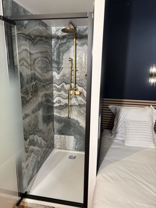 Douche moderne avec carrelage effet marbre et robinetterie en laiton dans la salle de bains de l'appartement ATHEA Paris