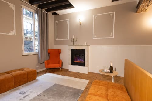 Salon moderne de l'hôtel ATHEA avec sièges orangés, cheminée et parquet chevrons à Paris