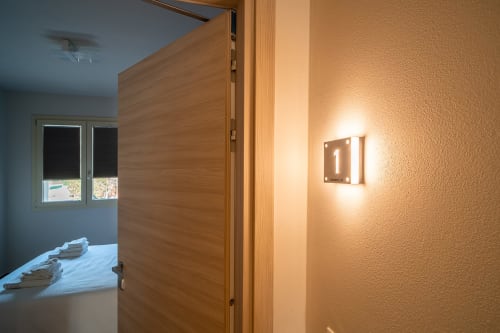 Ingresso Camera Adamello presso Le Alpi bed & living con porta in legno, insegna illuminata della camera 1 e finestre con vista montagna