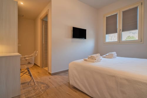 Camera luminosa presso Le Alpi bed & living con letto matrimoniale, TV, scrivania, pavimenti in legno e vista montagna dalle finestre