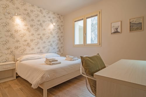 Camera luminosa di Le Alpi B&B con letto matrimoniale, vista sulle montagne, pavimenti in legno e carta da parati floreale
