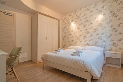 Camera moderna a Le Alpi bed & living in Italia con letto in legno, carta da parati a motivi floreali, armadio e viste montane