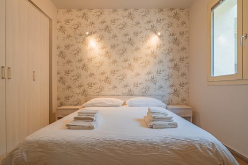 Camera moderna Le Alpi con carta da parati a motivi, letto matrimoniale, arredi in legno e vista montagna