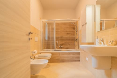 Bagno spa moderno presso Le Alpi b&b con arredi in legno, cabina doccia in vetro, doppi lavabi e pavimentazione in marmo