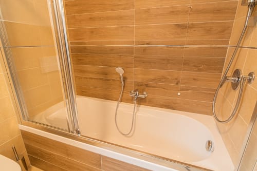 Bagno moderno con piastrelle effetto legno, vasca freestanding bianca e doccia in vetro a Le Alpi bed & living, Italia