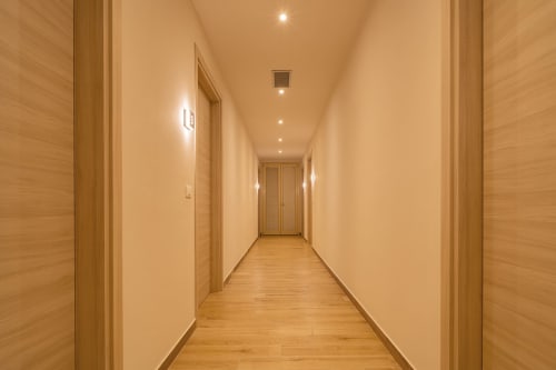 Corridoio moderno presso Le Alpi bed & living in Italia con porte in legno, illuminazione calda e pavimentazione in legno che conduce alle camere degli ospiti