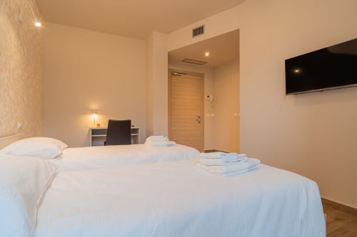 Moderna camera doppia presso Le Alpi bed & living in Italia con letti bianchi, TV a schermo piatto, scrivania e vista sulle montagne