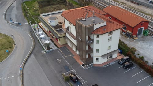 Vista aerea del bed & living Le Alpi: edificio alpino italiano con tetto rosso e parcheggio vicino alla ferrovia