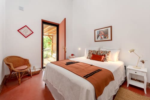 Quarto luminoso em Monte das Açoteias com cama branca, detalhes em terracota, portas com vista para o jardim e decoração tradicional portuguesa