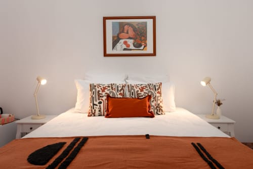 Quarto moderno em Monte das Açoteias com roupa de cama branca, detalhes terra e arte contemporânea em Tavira, Portugal