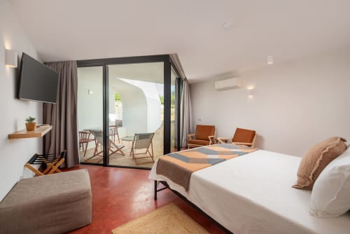Quarto estúdio moderno em Monte das Açoteias com vista para a piscina, cama, área de estar e portas de vidro para o terraço