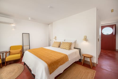 Quarto Mayor da Suite Moderna em Monte das Açoteias com detalhes amarelos, roupa de cama branca e piso de azulejo vermelho em Tavira