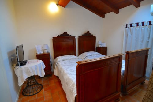 Camera da letto con mobili in legno presso la Corte delle Giuggiole B&B a Cologna Veneta, con letti, TV e pavimenti in cotto
