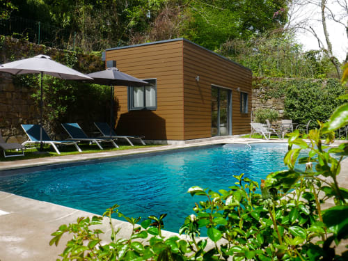 Maison de piscine moderne au Clos De La Gourmandière, Saint-Lothain, avec piscine turquoise, transats et jardin luxuriant.