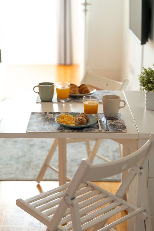 Mesa de café da manhã no Bom Porto Apartments com café, suco de laranja, croissants e cereais em apartamento brilhante no Porto