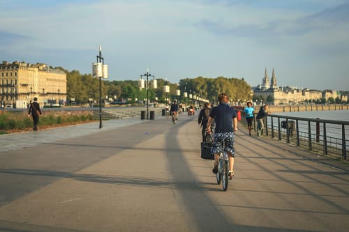 Cycliste sur la promenade fluviale de Bordeaux avec l'architecture historique et les vues sur la rivière