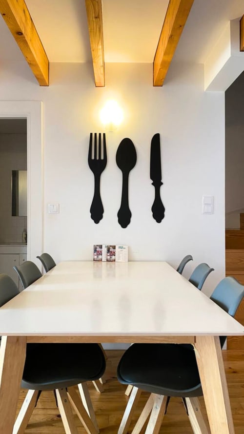 Sala de jantar moderna do Bom Porto Apartments com mesa branca, vigas de madeira e arte de parede com garfo, faca e colher decorativos