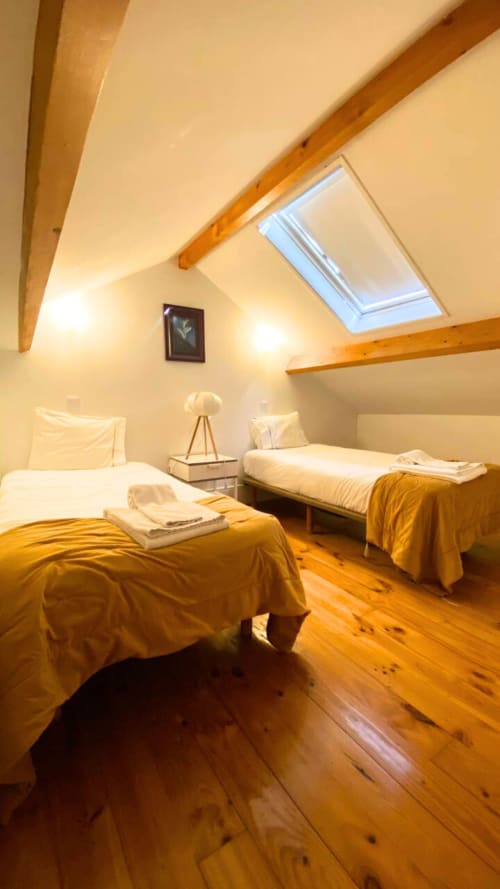 Quarto no sótão luminoso com duas camas individuais, vigas de madeira, claraboia e piso de madeira no Bom Porto Apartments, Porto