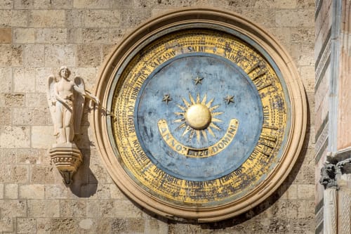 Raffinato orologio astronomico sulla facciata in pietra vicino a BellDuomo Suite a Messina, con anello dorato dello zodiaco e simbolo solare
