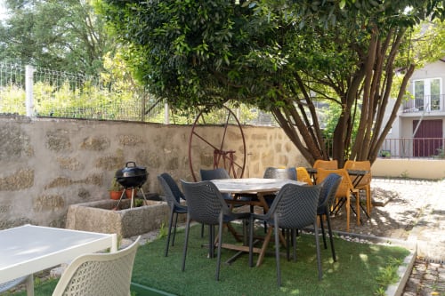 Pátio exterior do Bom Porto Apartments no Porto com mesa de jantar, cadeiras e árvores frondosas para sombra