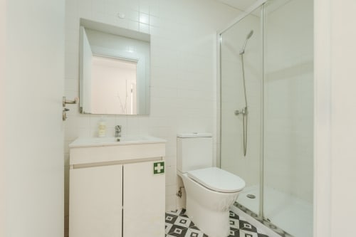Casa de banho moderna no Bom Porto Apartments Porto com azulejos brancos, lavatório, sanita e box de vidro