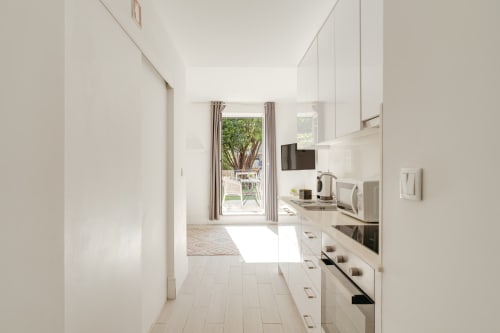 Cozinha moderna branca com vista para jardim no Apartamento Bom Porto Porto, T1 com terraço e área de estar exterior