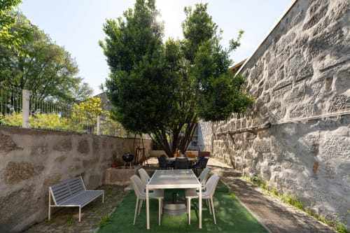 Terraço do Bom Porto Apartments com jardim, mesa de refeições, muros de pedra e árvores verdes no Porto