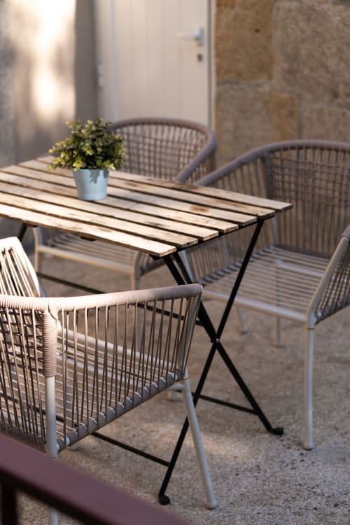 Terraço exterior moderno do Bom Porto Apartments com mesa de madeira, cadeiras de vime e planta em vaso