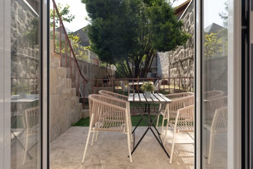 Terraço do Bom Porto Apartments com mesa de jantar e cadeiras trançadas vista para pátio de pedra no Porto