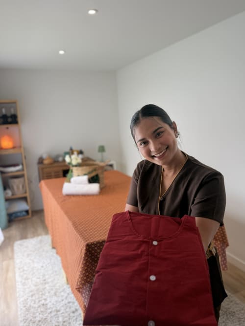 Membre du personnel souriant tenant des draps rouges aux Chambres d'hôtes Lady Jule spa à Sainte-Luce-sur-Loire