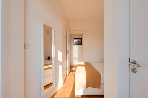 Corredor luminoso no duplex do Bom Porto Apartments com piso em madeira, portas brancas e vista para o jardim no Porto