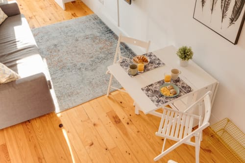 Área de refeições luminosa do Bom Porto Apartments com mesa branca, café da manhã, pisos em madeira e vista para o jardim no Porto